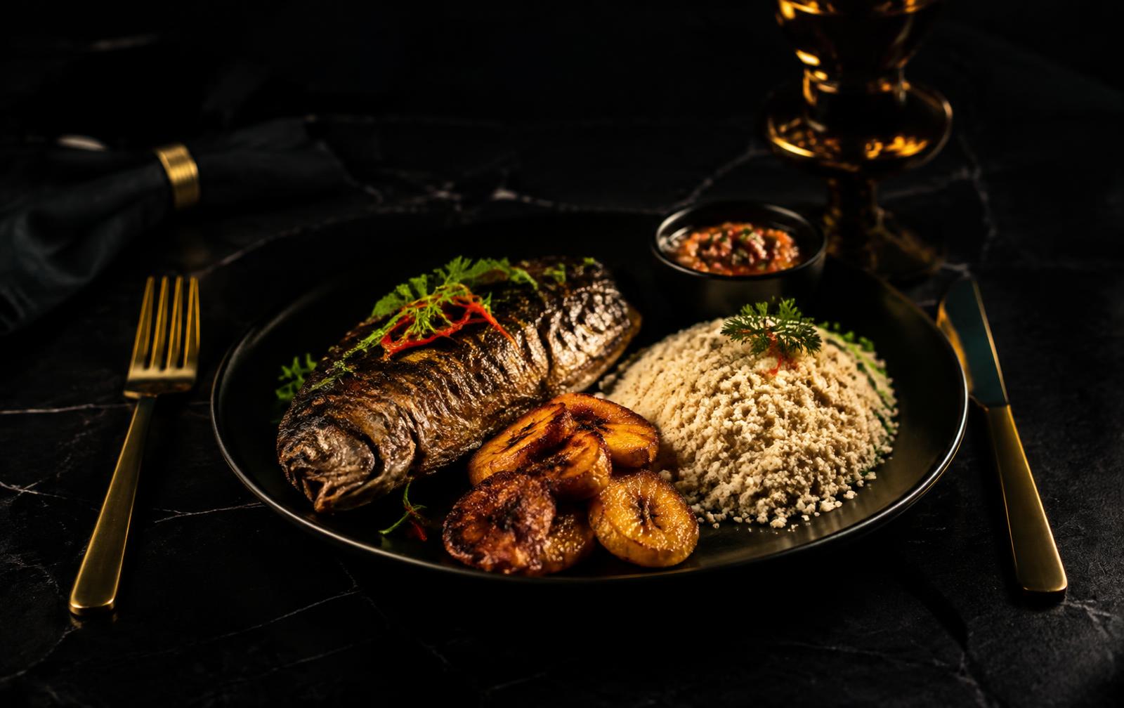 Poisson braisé, attiéké et alloco dressés sur assiette noire